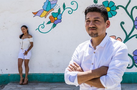 Man in the foreground with girlfriend in the background resting on the colorful wallの写真素材