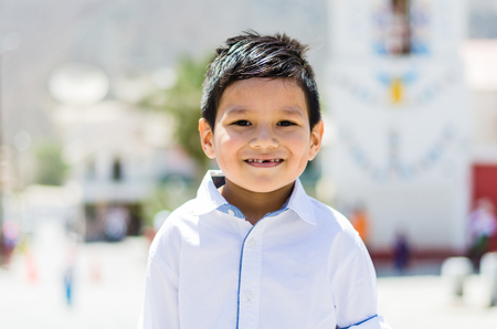 Boy in white shirt outdoors smiling without teethの写真素材