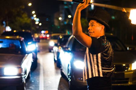 A street artist who makes a show in Lima - Peru, juggling a stick with fire at traffic lights stops, in front of stopped carsの写真素材