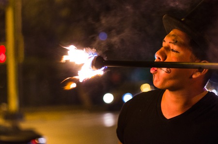 A street artist who makes a show in Lima - Peru, juggling a stick with fire at traffic lights stops, in front of stopped carsの写真素材