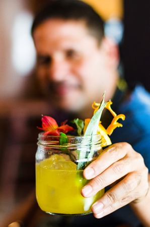 Young man smiling holding orange juice, closeup shotの写真素材