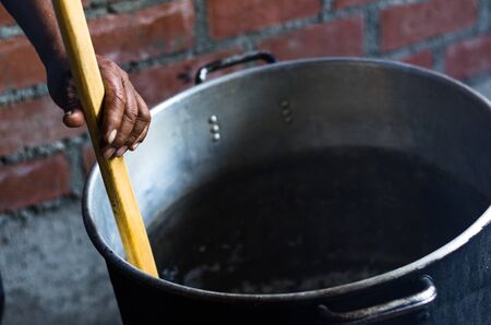 An Andean mans hand moving the wooden spoon in a pot, Andean rustic cuisineの写真素材