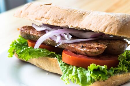 Meat sandwich with tomato and lettuce served on a baguette bread
