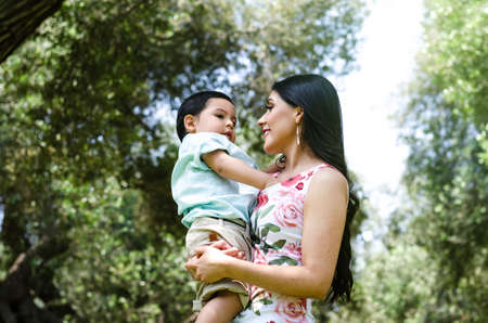 Cute portrait of mother holding her baby in autumn in the park. Concept for mothers day.の写真素材