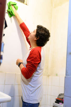 man cleaning white wall before painting while renovating interior.