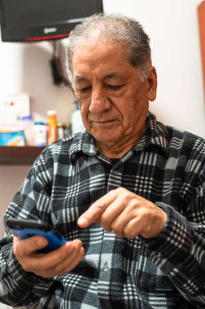 Happy senior Caucasian man looking at cellphone screen browse wireless internet. Smiling modern mature 70s grandfather text or message on smartphone. Elderly use cell technologies at home.の写真素材