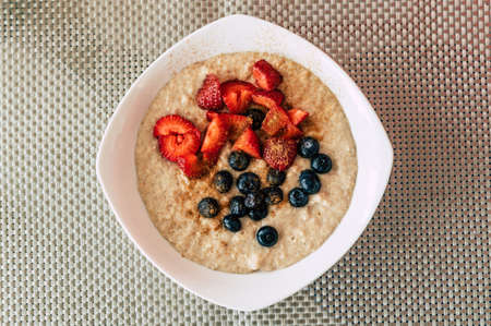 Homemade oatmeal with blueberries and strawberries in a bowl. Healthy breakfast. Top view.