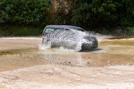 A mid-size van in puddles, mud and splashes. The Peruvian jungle in the background.