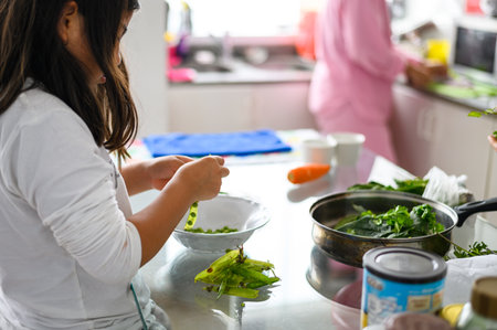 cleaning and help in the home. child development. little girl helping in the kitchen. little girl prepare healthy food at home.の写真素材