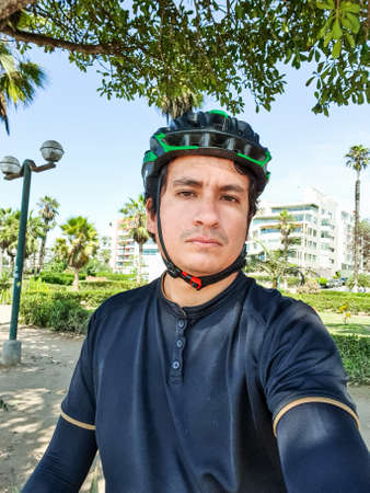 young handsome cyclist in black cycling clothing, wearing a helmet in a park.の写真素材