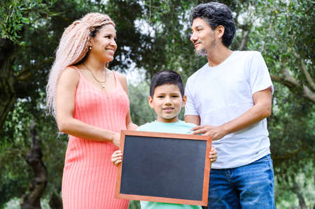 Beautiful happy family holding a blackboard with free space for text.の写真素材