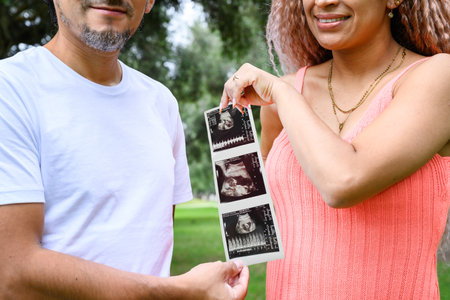Couple holding ultrasound outdoor and announcing pregnancy.