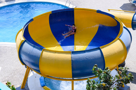 Child sliding down colorful water slide at poolの写真素材