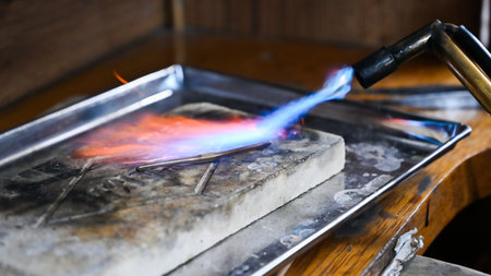 Blowtorch is heating metal to make a jewel in a workshop