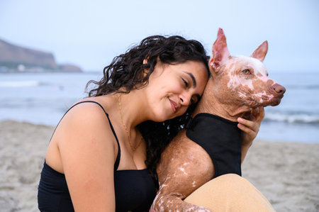 Young woman hugging her senior xoloitzcuintli dog on the beachの写真素材