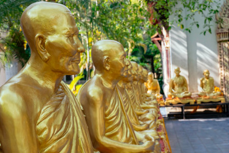 Golden monk statues in thai temple gardenの写真素材