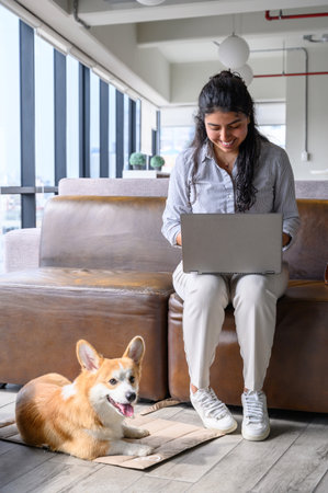Latin businesswoman working from home with her pet corgi dog