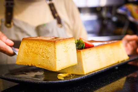 Chef serving slice of homemade flan with strawberries