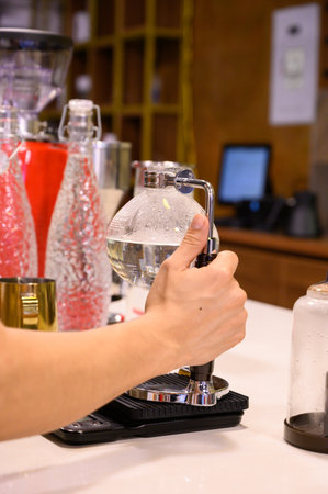 Barista brewing syphon coffee in cafe using scale