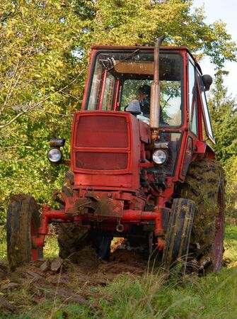 red old tractor in autumn on field の写真素材