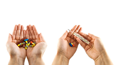 opened hands offering assorted pills and thermometerの写真素材