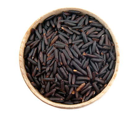 black rice heap in woden bowl top view surface close up isolated on whiteの写真素材