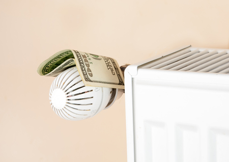 heating thermostat with money, hundred dollar, expensive heating costs conceptの写真素材