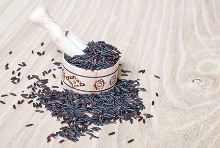 black rice in a wooden bowl on tableの写真素材