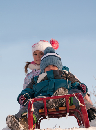 two kids sliding with sledding in the snowの写真素材