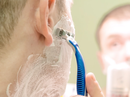 handsome man shaving his beard in bathroomの写真素材