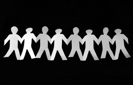 White paper cut into people hold their hands connected on black backgroundの写真素材