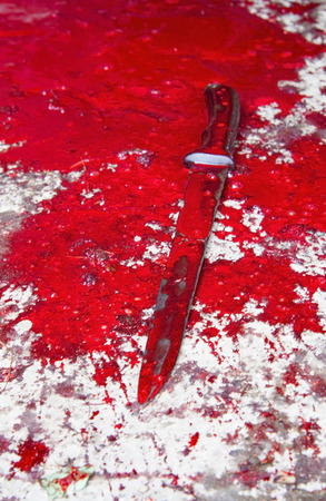 Conceptual image of a sharp knife with blood on it resting on a concrete floor. Concept photo of murder and crimeの写真素材