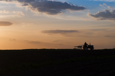 A silhouette of a tractor while the sunsets