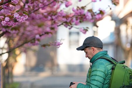 Photographer taking picture of pink Japanese cherry-tree in sunny spring day. Sakura.