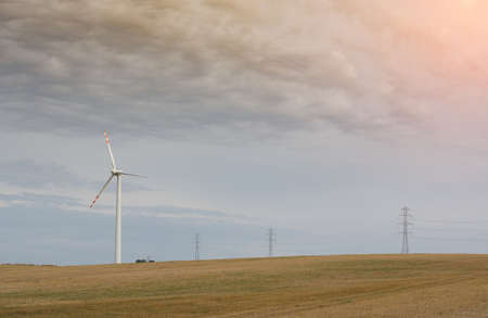 wind turbine in a field of wheat in summer with a sky