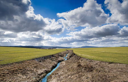 mountain landscape and green meadow with stream in the foregroundの写真素材
