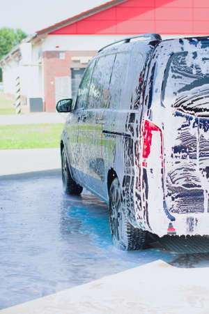 Manual car wash with soap, foam on the body. Washing Car Using High Pressure Water.