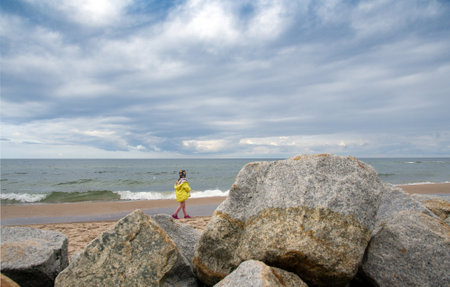 Girl is going looking at the restless sea in summer, overcast sky.の写真素材