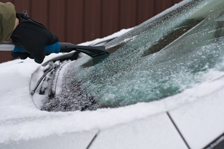 Winter scene, human hand in glove scraping ice from car