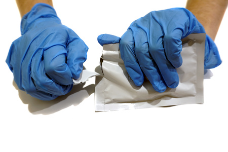 Hands in blue medical gloves tearing a pack for Human immunodeficiency virus testの写真素材