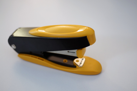 Yellow stapler on the white desk - office stationary