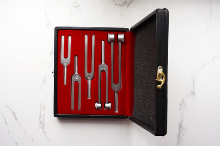 Case of Set of Tuning Forks for hearing tests on a marble background . Medical equipment. Medical...