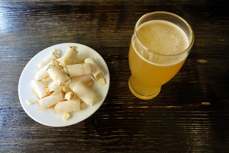 Delicious sliced pork fat with spices,  on plate with glass of beer on wooden background close up. Meat platter. Top viewの写真素材