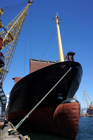 The massive bow of a large ship, with the radar dome above the surface of the water with crane, at the seaport. verticalの写真素材