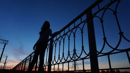 silhouette of a girl on the bridge during red sunset with deep blue sky.bottom view. Wideの写真素材