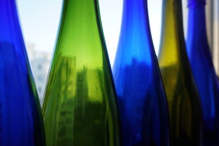 Green and blue wine and champagne translucent bottles against a window background. Home Decoration loft background.の写真素材