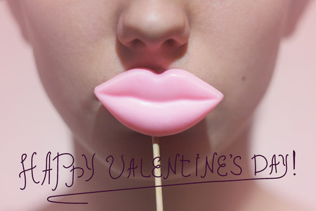 Beauty joyful Young Funny fashion model Girl holding big pink lips on a stick smiling, Beauty concept. On pink background. Frontal viewの写真素材