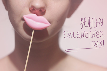 Beauty joyful Young Funny fashion model Girl holding big pink lips on a stick smiling, Beauty concept. On pink backgroundの写真素材
