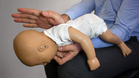 Back blows (the Heimlich maneuver or Heimlich manoeuvre) on a simulation mannequin infant dummy during medical training Basic Life Supportの写真素材