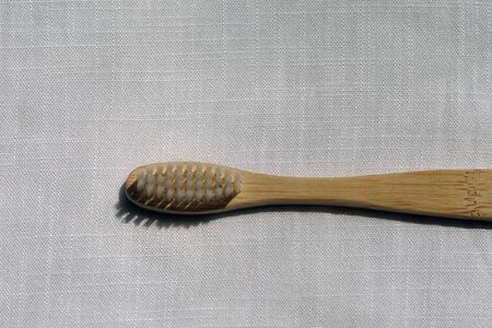 Close up of the Eco-friendly white bamboo toothbrush on a white linen background. Natural organic...